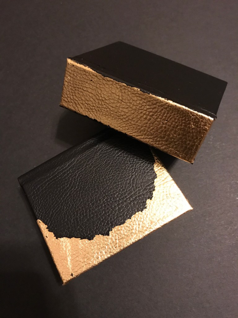 Photo of two tiny leather-bound books with gold leaf detail