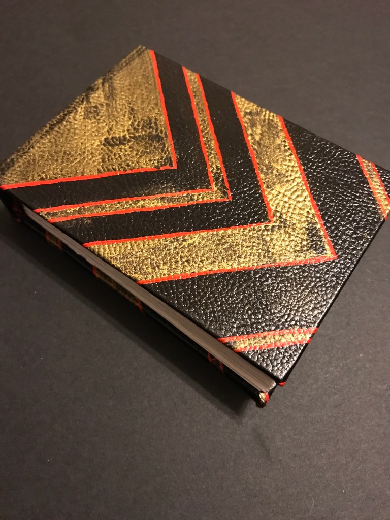 Photo of tiny leather-bound book with painted detail