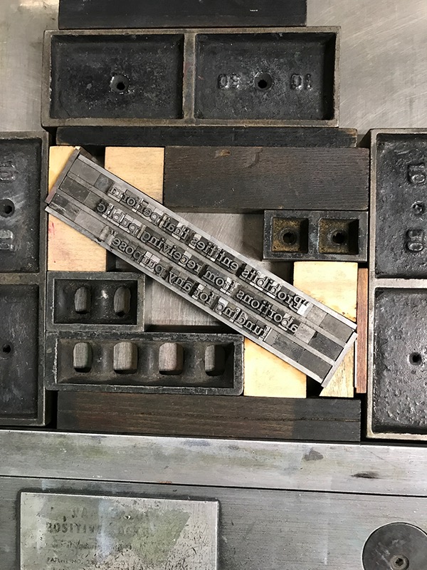 Photo of letterpress bed with small text set at an angle and letterpress furniture